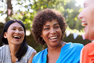 Multicultural group of middle-aged women smiling and laughing, showing off white teeth