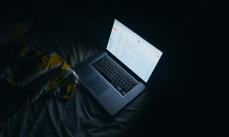 Blue light emitting from a laptop on a bed at nighttime can disrupt sleep
