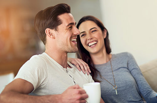  A couple laughing while enjoying a cup of coffee together