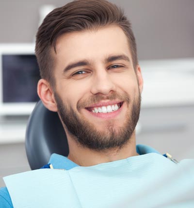 A young man smiling while sitting comfortably in the dental chair